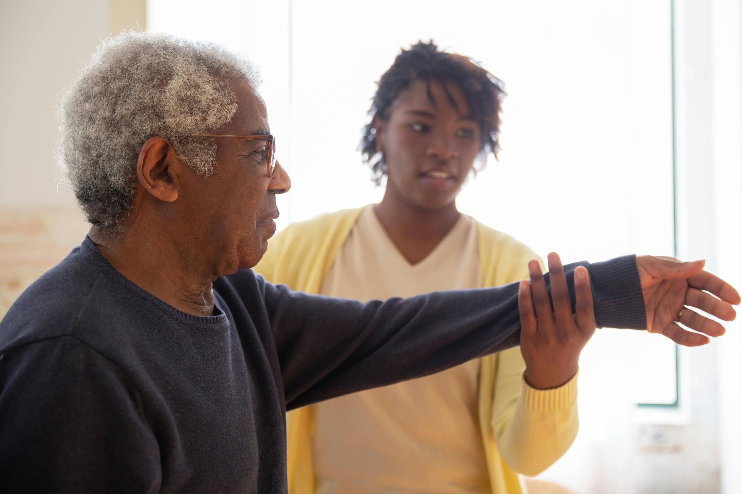An older adult and a care worker exercising together at home