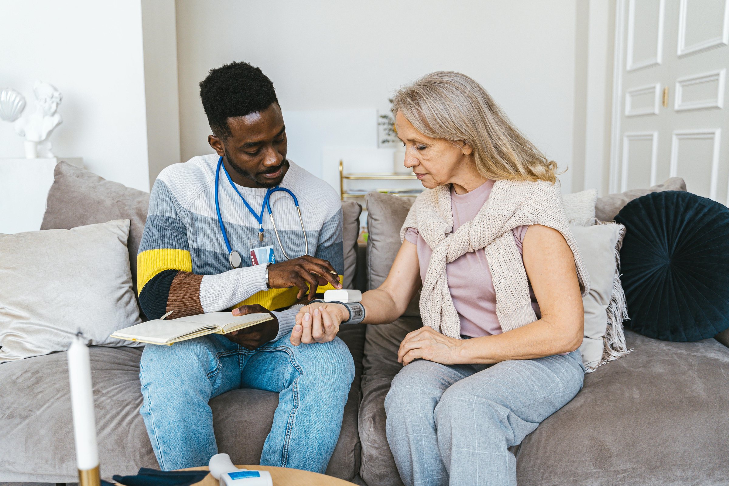 Care professional checking an older woman’s blood pressure at home
