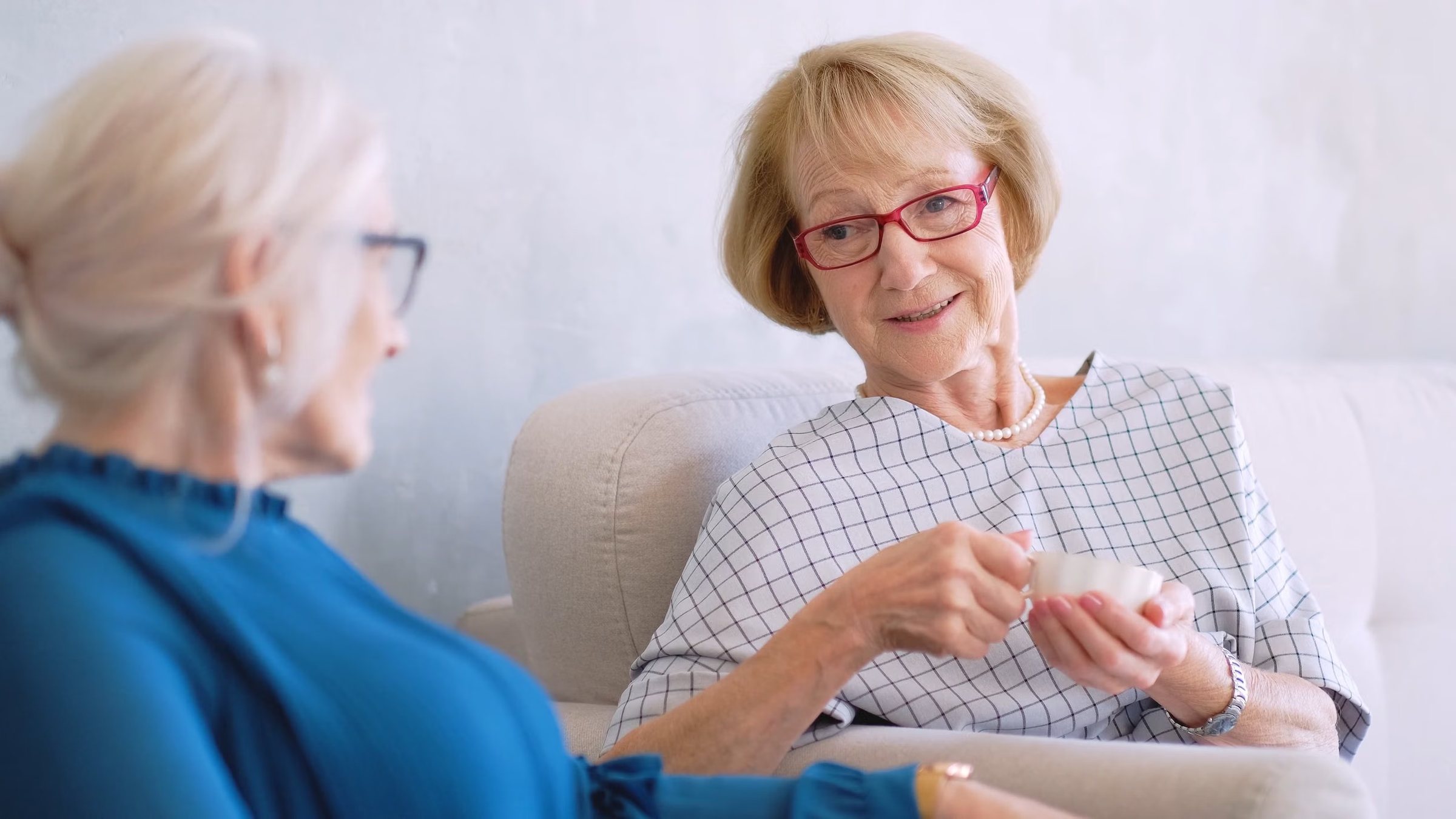 Two older women talking over tea at home